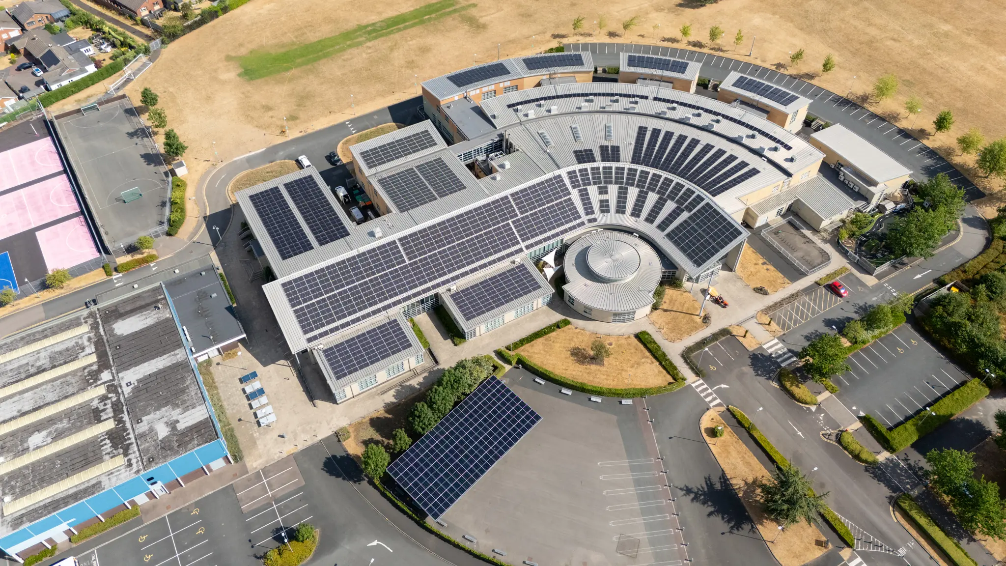 a school with a big solar pv system across the roof and solar canopy